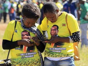 Supporters of ZANU-PF leader and Zimbabwean President Emmerson Mnangagwa look at their mobile phones during a gathering at Freedom Square in Harare, Wednesday, June, 6, 2018. Hundreds of youths gathered and marched briefly in solidarity with their leader ahead of polls set for July 30.