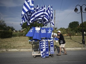 A vendor pushes his trolley with Greek flags during of a rally in Pella, northern Greece, on Wednesday, June 6, 2018. Hardline groups trying to pressure Greece's government into adopting a tougher stance in negotiations with northern neighbor Macedonia organize rallies in Pella, birthplace of ancient Greek warrior-king Alexander the Great, and other northern Greek towns. The T-shirts read in Greek ''Macedonia is Greek.''