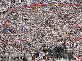 Supporters of the ruling Social Democratic party wait for the beginning of a rally outside the government headquarters in Bucharest, Romania, Saturday, June 9, 2018. Thousands of government supporters dressed in white massed in the Romanian capital to protest against what they call abuses committed by anti-corruption prosecutors.