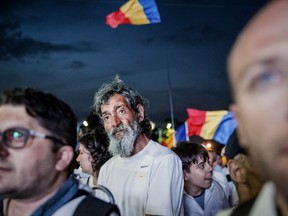 A man stands among supporters of the ruling Social Democratic party attending a rally outside the government headquarters in Bucharest, Romania, Saturday, June 9, 2018. Tens of thousands of government supporters assembled in the capital dressed in white to protest alleged abuses committed by anti-corruption prosecutors.