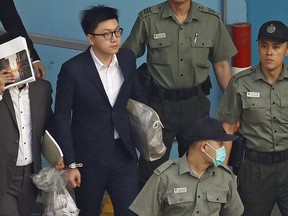 Hong Kong Activist Edward Leung, second left, is escorted by Correctional Services officers at a prison yard before boarding a bus to take him to high court for sentencing in Hong Kong, Monday, June 11, 2018. A Hong Kong court has sentenced Leung to six years in prison for his part in a violent nightlong clash with police over illegal street food hawkers two years ago.
