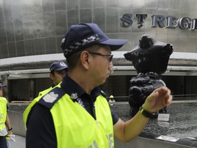 Singapore police officers patrol the grounds around the St. Regis hotel as traffic policemen start to barricade the roads surrounding it, on Saturday, June 9, 2018, in Singapore ahead of the summit between U.S. President Donald Trump and North Korean leader Kim Jong Un.