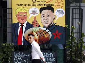 FILE - In this June 7, 2018, photo, a man walks past an advertisement board of cartoon caricatures of U.S. President Donald Trump and North Korean leader Kim Jong Un which are supposed to be the inspiration behind a local dish, the "Trump-Kim Chi Nasi Lemak" at a mall, in Singapore. Singapore is a city that takes great pride in its food, so it's not surprising that enterprising restaurateurs are using next week's historic summit between U.S. President Donald Trump and North Korean leader Kim Jong Un to showcase some culinary creativity. Restaurants are marking the city-state's time in the global spotlight with everything from red, white and blue cocktails to tacos named after the two leaders.