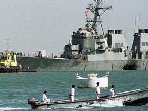 FILE - In this Oct. 29, 2000, file photo, a Yemeni police boat passes by the stricken USS Cole as it is pulled out of Aden port by Yemeni tugboats to deep water after an al-Qaida suicide attack in Aden, Yemen. Yemen's yearslong war between Shiite rebels and a Saudi-led coalition backing its exiled government has escalated with an assault on the insurgent-held port city of Hodeida.