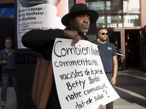 A protester walks through the sidewalk terrace as he takes part in a protest outside of the SLAV show, "a theatrical odyssey based on slave songs," directed by Quebec theatre luminary Robert Lepage.