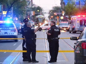 Toronto police attend the scene of a triple shooting on Queen St. West near Peter St. just before 8 p.m. on Saturday, June 30 2018.