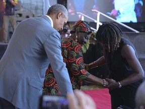Former US President Barack Obama, left and Auma Obama, right, help Obama's step- grandmother Sarah Obama  during an event in Kogelo, Kisumu, Kenya, Monday, July 16, 2018. Obama is in Kenya  to launch a sports and training center founded by his half-sister, Auma Obama.