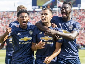 Manchester United midfielder Andreas Pereira, center, celebrates his goal with midfielder Demetri Mitchell, left, and defender Axel Tuanzebe, right, during the first half of an International Champions Cup tournament soccer match against Liverpool at Michigan Stadium, Saturday, July 28, 2018, in Ann Arbor, Mich.