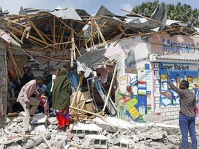 Somalis stand near the destroyed shops near Somali presidential place in Mogadishu, Somali, Saturday, July 14, 2018. Somali security forces shot dead three extremists and foiled an attempted al-Shabab attack on the presidential palace in the capital, a police officer said Saturday.