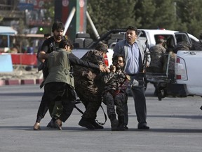 Afghan security personnel carry an injured comrade after an attack near the Kabul International Airport, in Kabul, Afghanistan, Sunday, July 22, 2018.