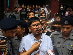 Detained Myanmar journalist Wa Lone (C) speaks to reporters as he is escorted by police from a courthouse following his ongoing pre-trial hearing in Yangon on July 9, 2018.