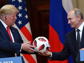 Russia's President Vladimir Putin (R) offers a ball of the 2018 football World Cup to US President Donald Trump during a joint press conference after a meeting at the Presidential Palace in Helsinki, on July 16, 2018.