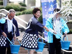 Tokyo Governor Yuriko Koike splashes water on the ground during a water sprinkling event called Uchimizu which is meant to cool down the area, in Tokyo on July 23, 2018.