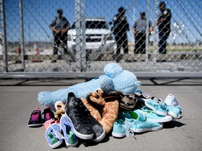 This June 21, 2018 file photo shows security personal standing before shoes and toys left at the Tornillo Port of Entry in Tornillo, Texas where minors crossing the border without proper papers have been housed after being separated from adults.