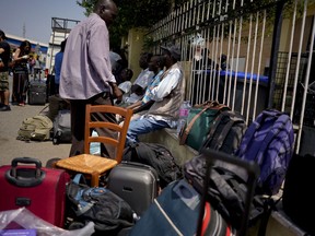 Migrants sit outside a building after being evicted by police in Rome, Thursday, July 5, 2018. Over 100 migrants, most of them refugees, were evicted from a squatted building in Rome.