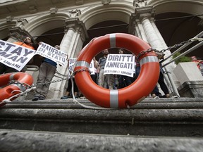 Protesters chains themselves outside the Ministry of Transport in Rome, Wednesday, July 11, 2018. Dozens of protesters chained themselves to the steps in a demonstration against the government's hard-line immigration policy. Writing on Italian signs reads "State shipwrecks, right to rescue, drowned rights."