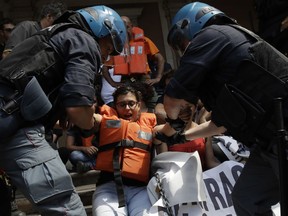 Protesters are dragged away by Italian police outside the Ministry of Transport in Rome, Wednesday, July 11, 2018. Dozens of protesters chained themselves to the steps in a demonstration against the government's hard-line immigration policy.