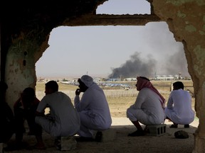 Jordanian residents of Jabir village watch aid deliveries to Syrians fleeing government offensive in the south as smoke from unknown fire rises, Tuesday, July 3, 2018. The UN says Syria government's Russian-backed offensive to recover southern territories from rebels has displaced 270,000 people, 60,000 of them headed near the sealed Jordanian borders.