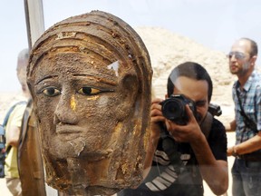 A photographer films a gilded silver mummy mask found on the face of the mummy of the second priest of Mut, as it is displayed during a press conference in front of the step pyramid of Saqqara, in Giza, Saturday, July 14, 2018. Archaeologists say they have discovered a mummification workshop dating back some 2,500 years at an ancient necropolis near Egypt's famed pyramids.