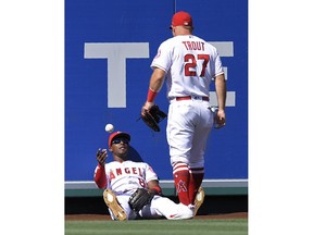 Los Angeles Angels left fielder Justin Upton, left, tosses the ball to Mike Trout after making a catch on a ball hit by Houston Astros' George Springer during the first inning of a baseball game Saturday, July 21, 2018, in Anaheim, Calif.