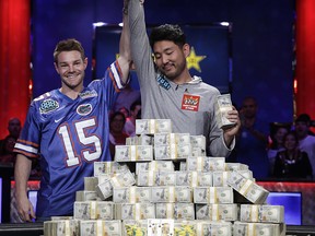 Tony Miles, left, holds up the arm of first place finisher John Cynn after the World Series of Poker main event, Sunday, July 15, 2018, in Las Vegas.