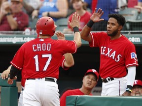 Texas Rangers' Shin-Soo Choo (17) celebrates his run scored with teammate Elvis Andrus on a single by Adrian Beltre against the Cleveland Indians during the first inning of a baseball game, Friday, July 20, 2018, in Arlington, Texas.