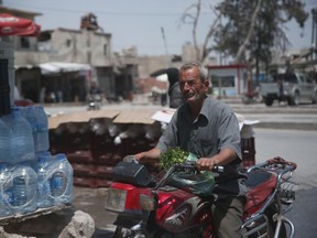 In this Tuesday, May 29, 2018, photo, a Syrian man drives his motorcycle in the centre of al-Bab, northern Syria. Nearly half of Syria's pre-war population of 23 million have been uprooted from their homes_ the overwhelming majority of them Sunni Muslims, who were among the first to rise against the government in 2011.
