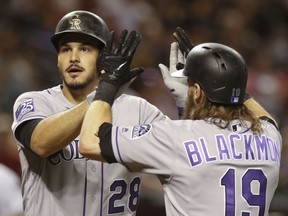 Colorado Rockies' Nolan Arenado gets a high-five from Charlie Blackmon after hitting a two-run home run off Arizona Diamondbacks' Robbie Ray during the first inning of a baseball game Friday, July 20, 2018, in Phoenix.