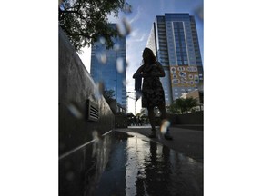 Phoenix city employee Tammy Vo stands by a water mister as she hands out cooling neckerchiefs to morning commuters early Monday, July 23, 2018, in downtown Phoenix. Parts of Arizona and the Southwest are bracing for the hottest weather of the year with highs this week expected to approach 120 degrees.