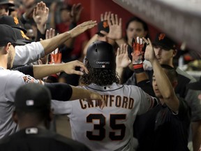 San Francisco Giants' Brandon Crawford (35) is greeted in the dugout after hitting a solo home run against the Arizona Diamondbacks during the second inning of a baseball game Saturday, June 30, 2018, in Phoenix.