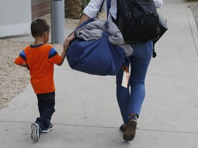 Three-year-old Jose Jr., from Honduras, is helped by representative of the Southern Poverty Law Center as he is reunited with his father Tuesday, July 10, 2018, in Phoenix. Lugging little backpacks, smiling immigrant children were scooped up into their parents' arms Tuesday as the Trump administration scrambled to meet a court-ordered deadline to reunite dozens of youngsters forcibly separated from their families at the border.