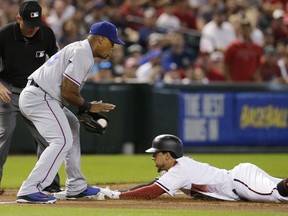 Arizona Diamondbacks Jon Jay, right, dives into third base after hitting a lead off triple in front of Texas Rangers third baseman Adrian Beltre in the first inning during a baseball game, Monday, July 30, 2018, in Phoenix.