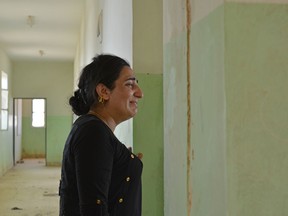 In this Tuesday, July 3, 2018 photo, provided by Yazda, a U.S.-based Yazidi rights group, Farida Khalaf weeps as she stands inside the schoolhouse where she had been separated from her family and first imprisoned in 2014, by Islamic State militants, in Kocho, northern Iraq. Khalaf somehow kept her composure as she returned to her devastated home village for the first time in four years -- until she entered the school. In a 2016 book titled "The Girl Who Beat ISIS: My Story," Khalaf described rape, torture and beatings at the hands of the extremists, and her escape after four months of captivity. (Yazda via AP)