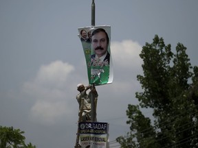 A worker of local administration removes banners of Tariq Fazal of Pakistan Muslim League headed by former prime minister Nawaz Sharif in Islamabad, Pakistan, Thursday, July 5, 2018. The Election Commission of Pakistan (ECP) issued a code of conduct and impose a ban on the use of large panaflex banners and posters as well as wall chalking. Pakistan will hold general election on July 25.