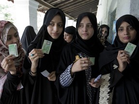 Pakistani women voters pose with their identity cards waiting to cast their vote in Rawalpindi, Pakistan, Wednesday, July 25, 2018. After an acrimonious campaign, polls opened in Pakistan on Wednesday to elect the country's third straight civilian election.