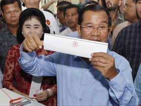 FILE - In this Sunday, July 29, 2018, file photo, Cambodian Prime Minister Hun Sen holds his ballot at a polling station in Takhmua, Kandal province, southeast of Phnom Penh, Cambodia. Determined to extend his 33 years as Cambodia's strongman ruler, Prime Minister Hun Sen was not about to let an election derail what he believes is his destiny. The 65-year-old Hun Sen had declared he intends to stay in office for 10 more years, and Sunday's general election victory by his Cambodian People's Party should get him halfway to that goal.