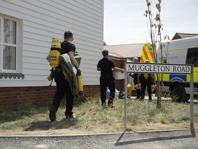 British firefighters carry equipment towards a property being searched on Muggleton Road in Amesbury, England, Friday, July 6, 2018.