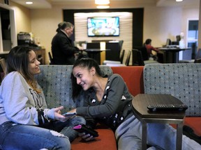 FILE - In this Feb. 27, 2018, file photo, 15-year-old Alanis Rodriguez, left, of Canovanos, Puerto Rico, and 14-year-old Bethel Sanchez, right, of Isabela, Puerto Rico, spend time together in a hotel lobby in Dedham, Mass. where they have lived temporarily after Hurricane Maria hit the island in September. A hearing is planned Monday, July 2, 2018, in Springfield, Mass., on a federal judge's restraining order temporarily blocking the evictions of nearly 1,700 Puerto Rican hurricane evacuees from hotels across the U.S.