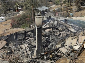 Firefighters stand near the charred remains of a home burned in a wildfire in Alpine, Calif., Saturday, July 7, 2018.