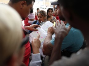 Names are read off a list of people who will cross into the United States to begin the process of applying for asylum Thursday, July 26, 2018, near the San Ysidro port of entry in Tijuana, Mexico.