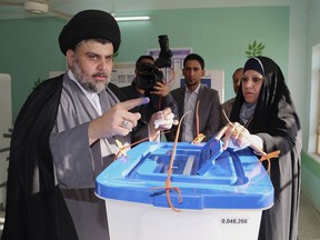 FILE - In this April 30, 2014 file photo, Shiite cleric Muqtada al-Sadr casts his vote at a polling station in the Shiite holy city of Najaf, 100 miles (160 kilometers) south of Baghdad, Iraq. The election commission began Monday, July 9, 2018 the manual recount for more ballots from parliamentary elections held in May that were marred by allegations of fraud and irregularities. The recount will further complicate the fragile post-elections period and prolong the process of forming the new government.