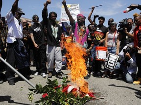 People chant slogans as they burn a U.S. flag outside the Los Angeles office of U.S. Rep. Maxine Waters, Thursday, July 19, 2018, in Los Angeles. A crowd gathered at the field office to counter a protest by a self-styled militia group burned the flag taken from the back of a pickup truck that drove up to the scene.
