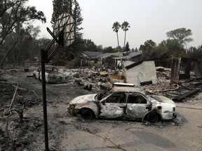 Burned vehicles sit in front of a wildfire-ravaged home, Sunday, July 29, 2018, in Redding, Calif.
