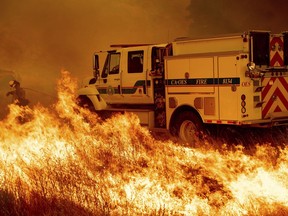 A firefighter scrambles to stop the Pawnee fire as it spots across Highway 20 near Clearlake Oaks, Calif., on Sunday, July 1, 2018.