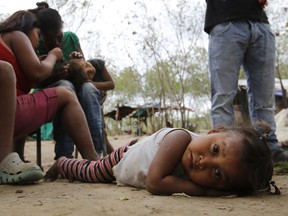 In this June 26, 2018 photo, a Venezuelan indigenous Yupka girl plays on the ground while another gets lice picked from her head at a camp set up in Cucuta, Colombia, near the border with Venezuela. Along the banks of the Tachira River dividing Colombia and Venezuela, many of the indigenous children have lice and distended bellies from malnutrition or parasites. Tribe leader Dionisio Finol said they are better off there than in Venezuela, where at least they can eat.