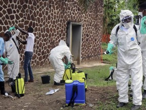 In this file photo taken Thursday, May 31, 2018, Congolese health officials prepare to disinfect people and buildings at the general referral hospital in Mbandaka, Congo.