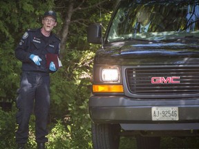 A member of the Toronto Police Service chats with a man in an unmarked vehicle on a property along Mallory Cres. in Toronto during an investigation relating to Bruce McArthur on Wednesday, July 4, 2018. Toronto police say they will be providing an update today in the case against alleged serial killer McArthur.