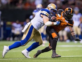 Winnipeg Blue Bombers' Adam Bighill, left, hits B.C. Lions' Chris Rainey during the second half of a CFL football game in Vancouver on July 14, 2018.