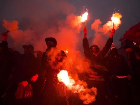 Toronto FC fans hold flares as they walk to BMO field for their team's MLS Eastern Conference semifinal match against the New York Red Bulls, in Toronto on Sunday, November 5, 2017. They march to the stadium in packs, clad in scarves and jerseys, chanting anthems and banging drums. They stand through entire games, cheering until hoarse. They're soccer fans, after all.