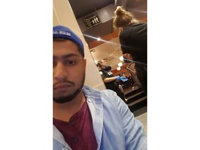 Demetre's Cafe employee Md Ashaduzzaman is seen alongside police and colleagues in a July 22, 2018, handout image. Md Ashaduzzaman was working a routine kitchen shift at a cafe in Toronto's Greektown when he heard the gunshots. The screams broke out moments later, among them were cries of a woman calling for someone to help her daughter.